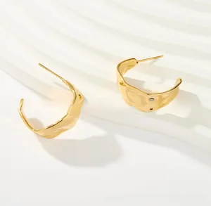Detail of gold titanium steel earrings with irregular water wave texture and polished finish