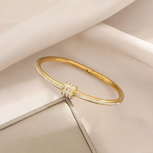 Detailed close-up of golden stainless steel bangle with double-row pavé crystals and rings