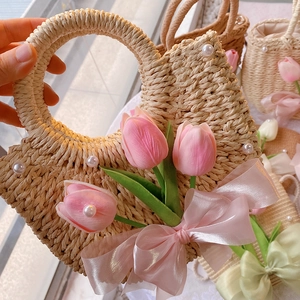 Detail of straw woven bag with pink silk tulips, faux pearls and ribbon bow decoration
