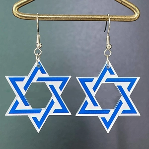 Macro close-up of blue acrylic Star of David earrings hanging on a metal display stand