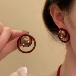 Macro view of geometric round earrings featuring red matte texture and metallic center