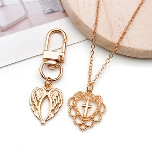 Detail shot of KC gold openwork heart LOVE pendant on a rustic wooden stand with accessories