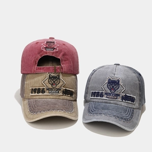 Close-up of vintage washed baseball caps with wolf patch embroidery and frayed edge detail