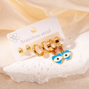 Detail of gold stainless steel earring set with blue evil eye charms on marble