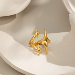 Detailed close-up of 18K gold star ring with geometric celestial design on white marble background