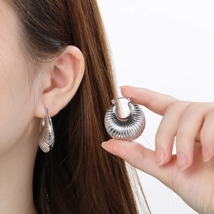 Detailed view of silver U-shaped hoop earrings with vertical ribbed texture on ear