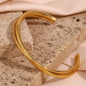 Detailed close-up of double-layer gold plated open bangle on elegant beige stone surface