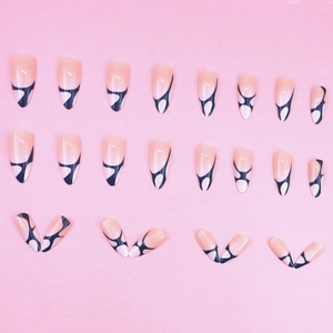 Nude stiletto press-on nails with black art lines and white dots in 24-piece set
