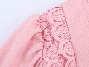 Close-up of pink dress lace stitching and textured fabric showing hollow embroidery