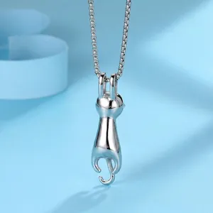 Minimalist cat pendant necklace in polished silver steel hanging on a soft blue background