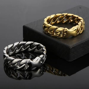Close-up of polished gold and silver Cuban chain bracelets with thick mechanical clasps
