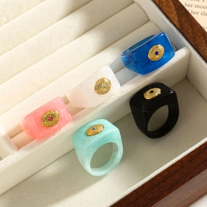 Detailed view of colorful resin rings with gold star emblems in a velvet box display