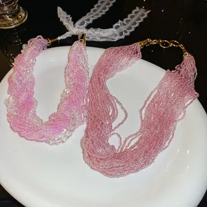 Layered pink bead and pearl choker necklace with gold clasp shown on a white plate