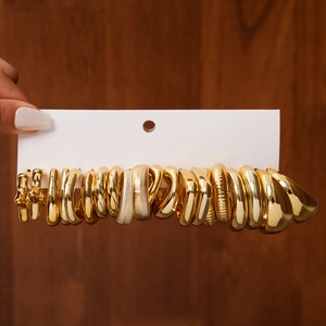 Macro shot of 10 pairs of golden hoop earrings set on a white card against wood