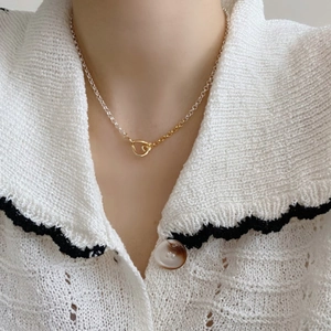 Detail of a minimalist two-tone silver and gold heart pendant necklace on model
