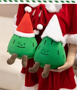 Detail of soft green Christmas tree plush toys with cute hats held by a model