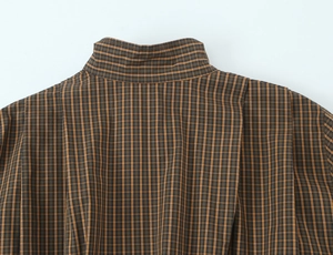 Macro detail of the collar and woven texture on a brown plaid checkered cotton shirt