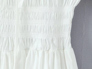 Détail du tissu blanc de la robe montrant la taille élastique froncée et la texture