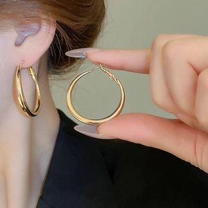 Detailed view of large polished gold hoop earrings featuring a secure pin closure design