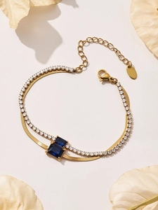 Detail of double-layer gold chain bracelet with blue square stones and clear zircon accents