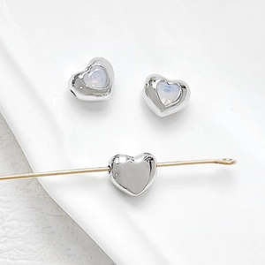 Macro detail of 18k silver plated heart beads with opal stones for DIY jewelry making