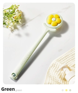 Detailed view of long-handled green body shower brush with yellow flower detail
