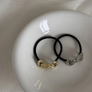 Detail view of gold and silver metallic bow hair ties on white ceramic background