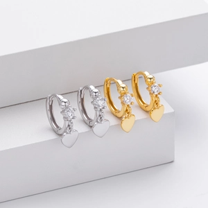 Macro shot of silver and gold heart hoop earrings with cubic zirconia on white steps