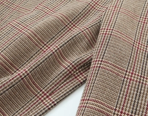 Close-up of thick houndstooth wool fabric in brown, red and beige with fiber details