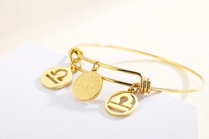 Detail of adjustable gold Libra zodiac bracelet with engraved charm and star symbols