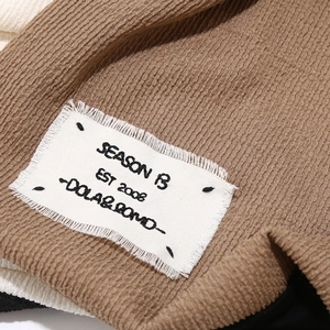 Macro shot of vertical textured beige knit fabric with vintage white woven brand label