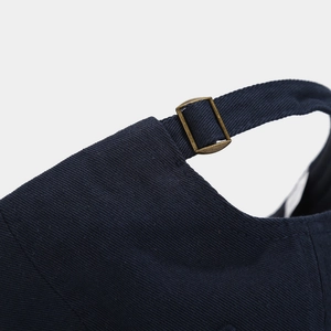Adjustable brass metal buckle detail on a navy blue cotton twill baseball cap back