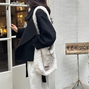 Close-up of white fuzzy shearling tote bag with wide strap for winter fashion look
