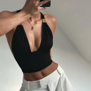 Detail eines schwarzen Neckholder-Tops mit goldenen Metallschnallen und V-Ausschnitt