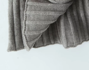 Detailed close-up of light grey ribbed knit fabric showing soft texture and premium craftsmanship