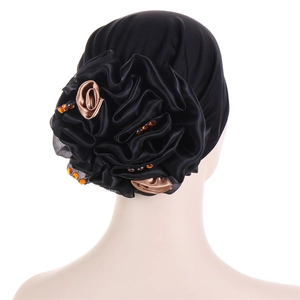 Detail of black turban hat featuring large 3D fabric flower with gold satin and orange rhinestones