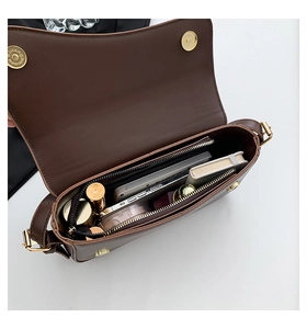 Detail view showing organized interior of brown leather shoulder bag with gold hardware