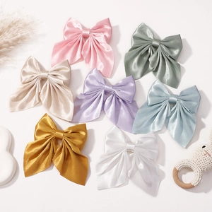Detailed flat lay of satin bow hair clips in multiple pastel colors with a soft silk texture