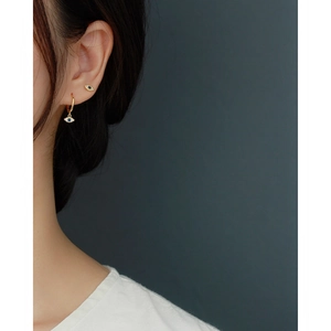 Detailed view of evil eye earrings set in gold with blue stones on a model