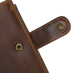 Detail of vintage brown genuine leather wallet with brass snap fastener and orange stitching