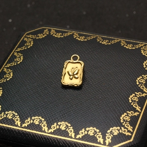 Detailed view of golden butterfly pendant with textured border on black jewelry box