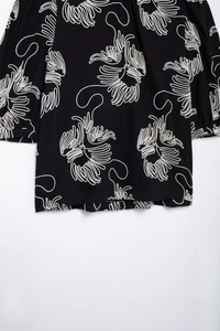 Detailed view of white embroidery on black cotton-linen zen-style blouse fabric
