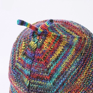 Detail of colorful knitted beanie showing multi-color mixed weave texture and top knot