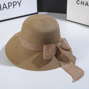 Detailed texture of hand-woven straw hat featuring a brown mesh ribbon bow decoration