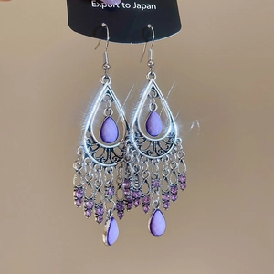 Detail of silver bohemian earrings featuring purple waterdrop gems and tassel fringe