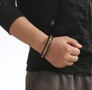 Detail of men's woven leather bracelet with gold metal blocks on male model wrist