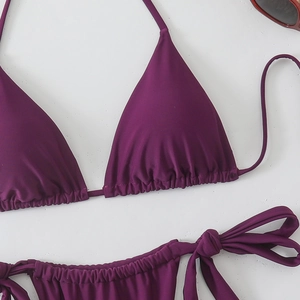 Dettaglio flat lay di un bikini a triangolo viola scuro con lacci regolabili al collo