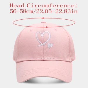Detail of pink cotton baseball cap featuring white heart embroidery and size dimensions