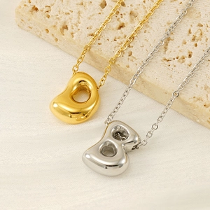 Polished gold and silver stainless steel bean pendant necklaces on stone display