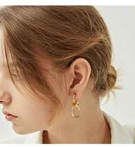 Detail of 18K gold-plated titanium steel knotted earrings worn by a model in warm light